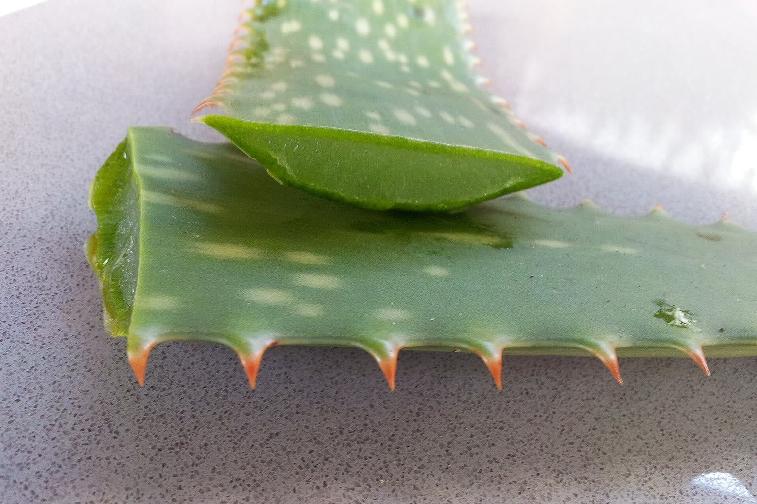 A cut aloe vera leaf showing the clear inner gel on a cutting board.