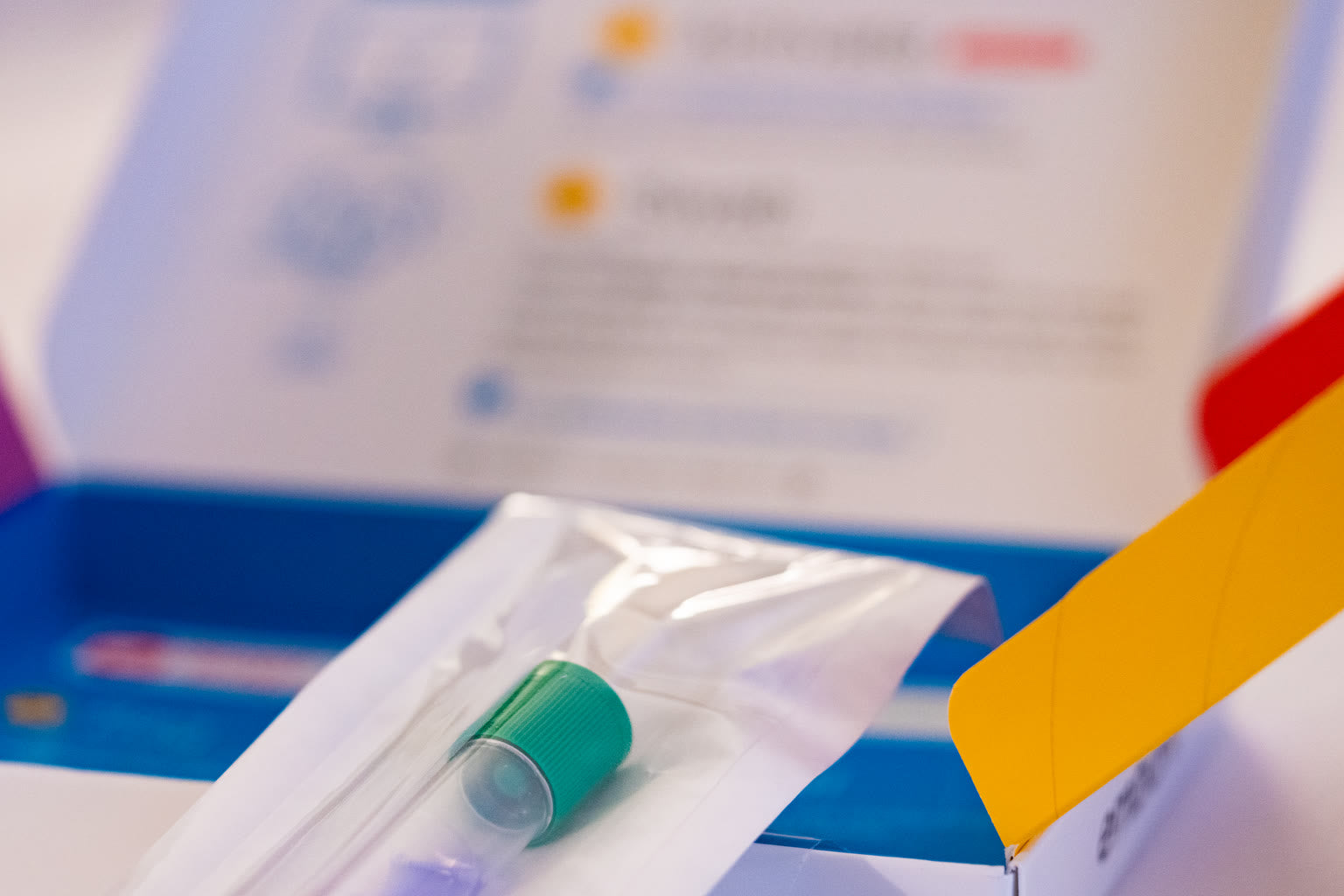 An at-home test kit box and collection tube on a clean bathroom counter.