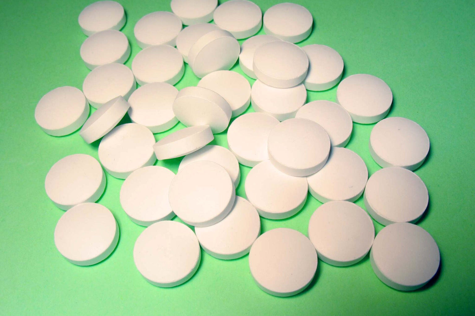 Chewable DGL tablets in a small dish beside a licorice root piece.