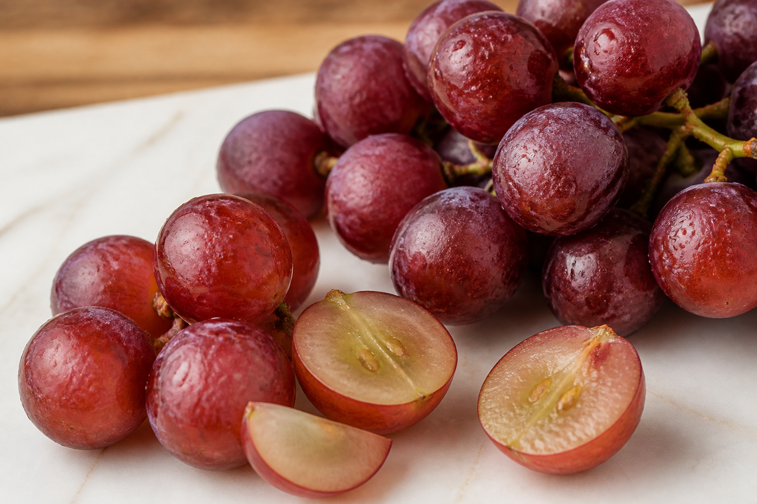 Close-up of Grapes as fresh whole and cut fruit on a clean wooden or marble surface