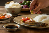 Hand seasoning a plate beside a small dish of patis or toyo