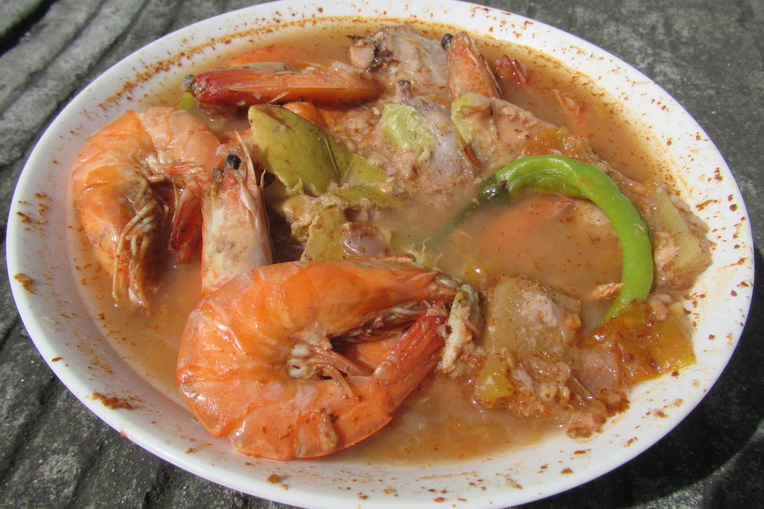 Two identical sinigang plates with rice on a rattan table