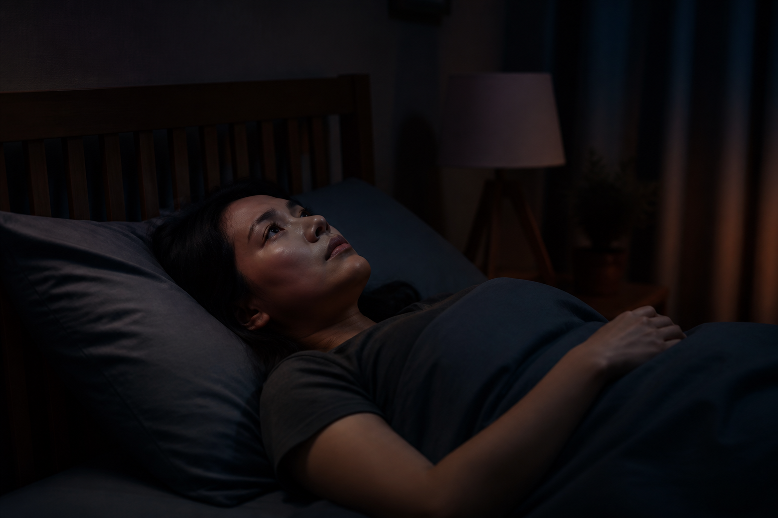Filipino woman in her 30s awake at 2am in a dark bedroom
