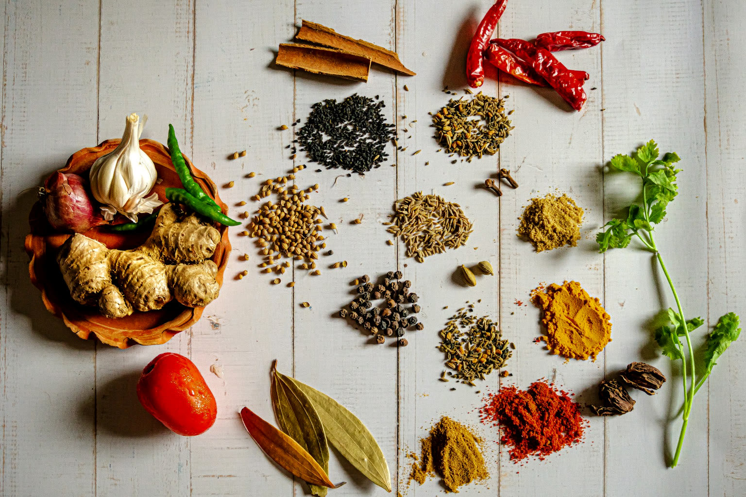 Dried herbal root pieces and powder in a wooden bowl beside a cup of tea.
