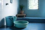 Clean Filipino bathroom with tabo and pail beside a tiled floor