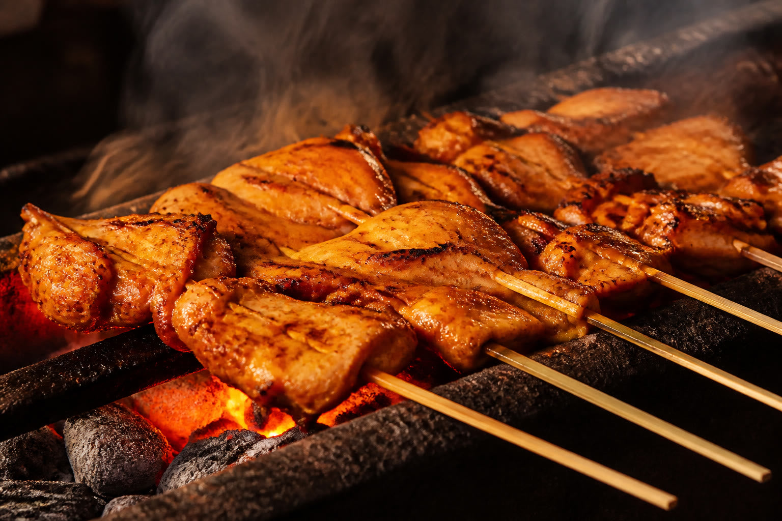 Inasal-style chicken skewers grilling over glowing charcoal